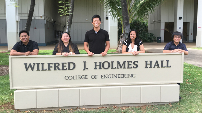 people standing in front of sign and smiling