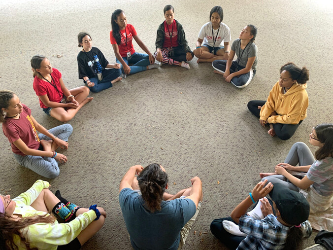 People sitting in a circle with their eyes closed