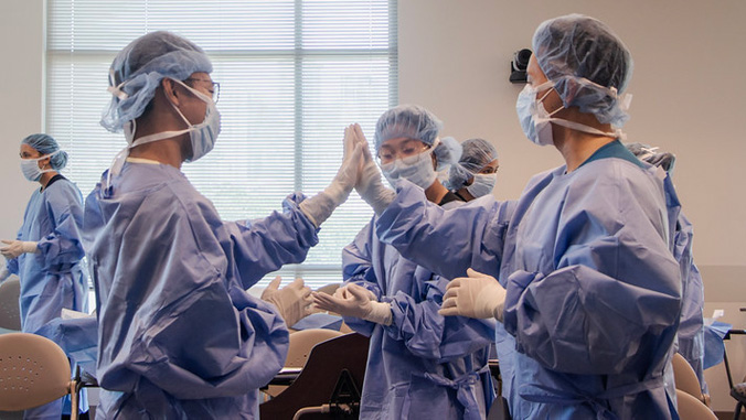 Medical students in P P E giving high fives