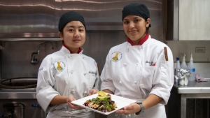 Two student chefs holding their dish of Mushroom Cauliflower Rice with Mushroom Teriyaki Chicken Glaze