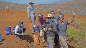 people pose for a photo while planting plants