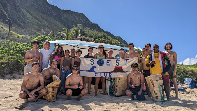 students at the beach holding a sign