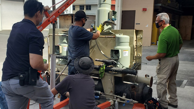 Students working on a chiller under the supervision of an instructor