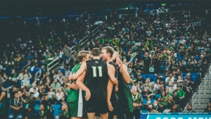 players huddled in a circle while people in stands cheer