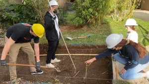 four people in hard hats digging soil