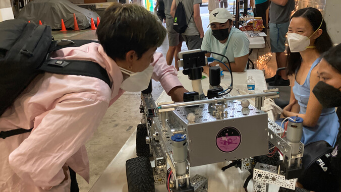 person in a pink shirt looking at a robot car