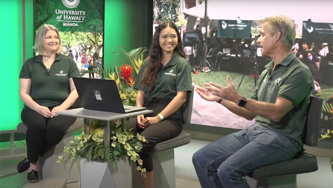 three people sitting on a set smiling