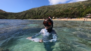 person in scuba gear above water in a bay