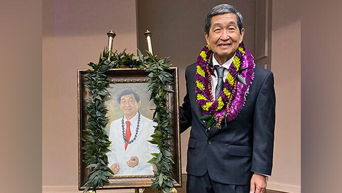 person with a suit and lei standing by a painting