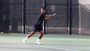 person in a black shirt with a tennis racket