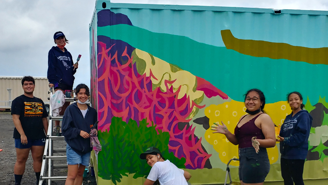 students standing next to mural