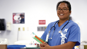 student wearing scrubs and holding books
