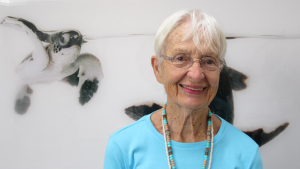 person smiling with a turtle painting behind