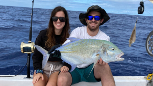 two people sitting on a boat holding a fish