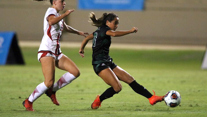 U H soccer player kicking a ball