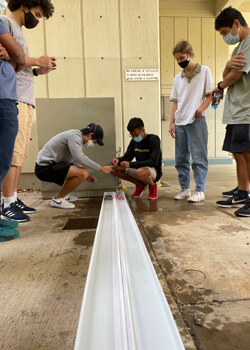 people looking at a toy boat on a course