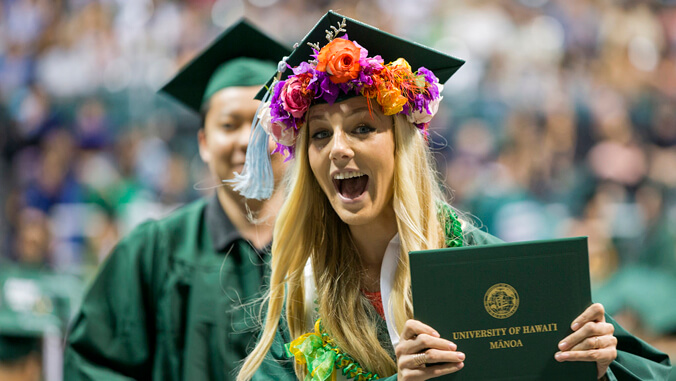person with a cap and gown holding up diploma