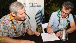 two people sitting on a desk signing a piece of paper