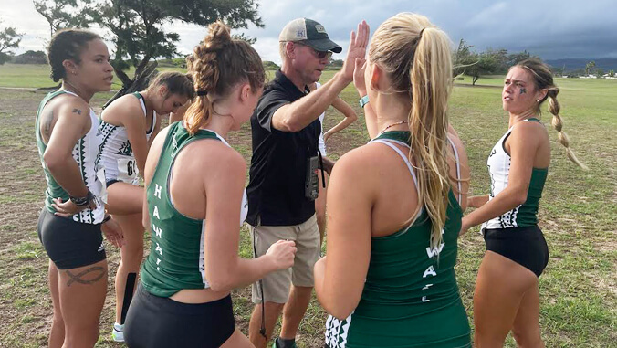 Cross country team huddled on field