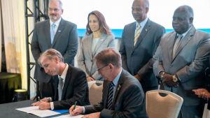 two people signing documents and four people watching