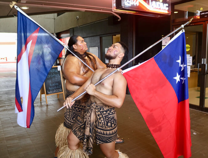 Two students proudly holding flags of Samoa