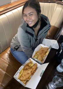 Person in a booth smiling over two servings of fish and chips