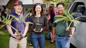 three people smiling with plants and trees