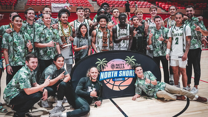 U H men's basketball team with North Shore Classic banner