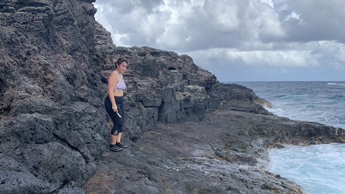 woman standing by ocean collecting opihi