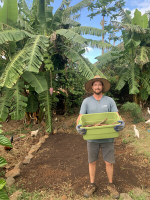 Balazs holding container in front of banana trees
