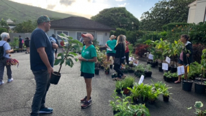 people talking to each other and standing next to plants