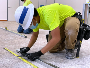 man in construction clothes measuring something on the floor