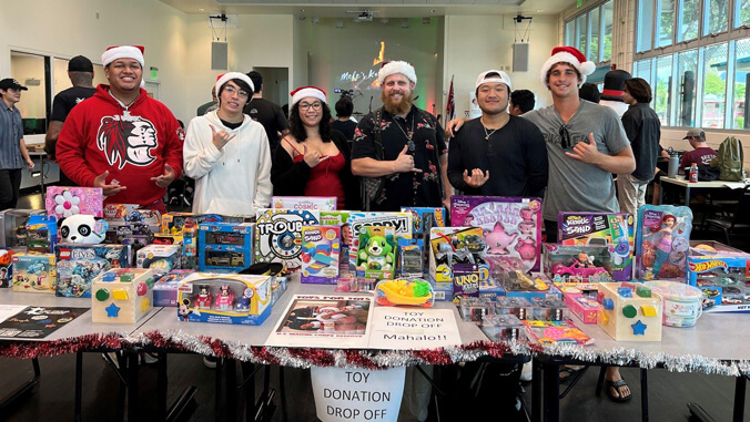 Smiling students standing behind a table full of donated toys