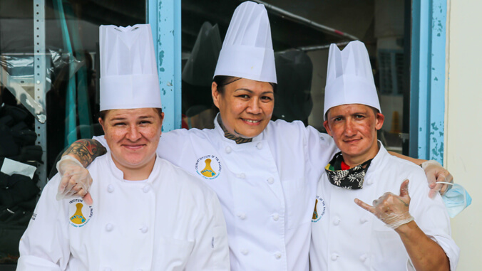 Three smiling students in chef hats