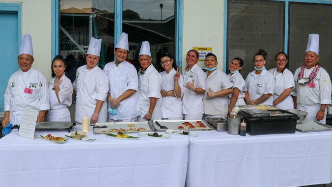 Students and instructors behind a table with food