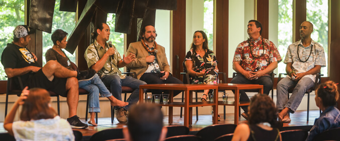 Seven people sitting on stage