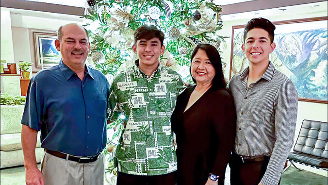 Four smiling people in front of a Christmas tree