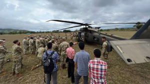 People stand around a large military helicopter