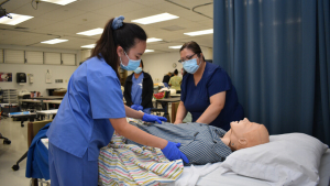 Students in scrubs working with a patient simulation