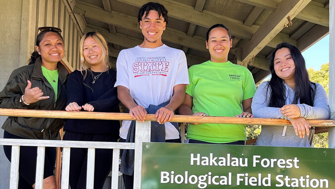 U H Hilo students standing behind railing