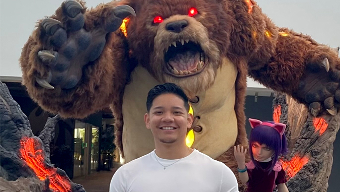 person smiling with a bear sculpture in the background