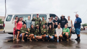 Group of people smiling and posing in front of a van