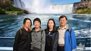 four people smiling at the camera with a waterfall in the background