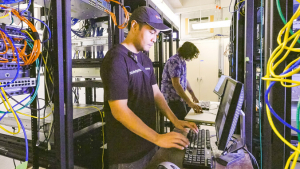 two people working on computers in server room