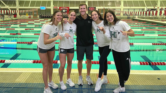 Group of people smiling in front of a pool