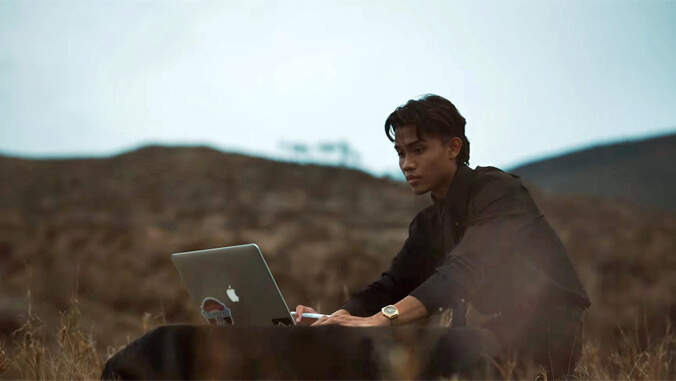 Ken Alba on a laptop sitting outside