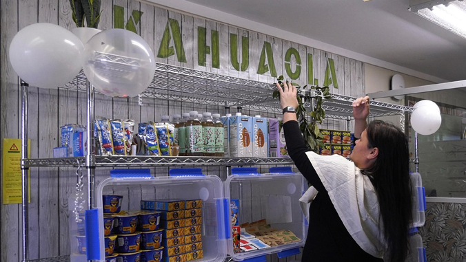 person putting a lei on top a shelf with food