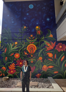 student standing in front of mural