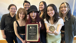 A group of people smiling and holding a plaque and medallion