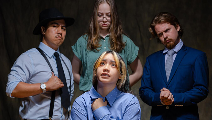 One person seated while three people stand behind with judgmental expressions